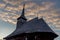 Side view of an old wooden church with bell tower on a cloudy blue sunset sky in Maramures