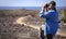 Side view of one senior man with binoculars looking at the horizon - walking outdoor in the footpath - arid landscape with cactus