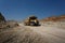 Side view of one yellow tip truck with a shadow on a natural background. Huge transporter in a sandy quarry.