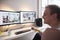 Side view, one young mans head looking at two monitors in front of him. in his room. keyboard, mouse and speakers visible at desk