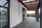 Side view of an open veranda in front of a modern forest cottage. Pine young forest under the sunset rays in the