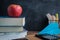 Side view over a wooden desk with school supplies on it. Stepler, colored pencils, notebooks, calculator, scissors, tapes, paints