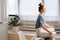 Side view of peaceful redhead young woman is meditating while sitting on desk at home office.