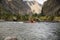 side view of people on kayaks rafting on mountain river and beautiful landscape,