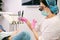 Side view photo of woman dentist in dental loupe binoculars, medical gloves and mask holding tools for curing the