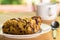 Side view piece of apple pie in a white dish and a cup of coffee, metal spoon