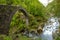 Side View on the Ponte Romano Intragna Bridge hiding in the valley with beautiful river covered with trees, close to