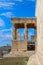 Side view of the Porch of the Caryatids with a bird flying in a very blue sky on the Erechtheion temple dedicated to Athena and Po