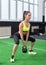 Side view portrait of an athlete woman doing exercises lifting kettlebell in gym working out back, legs muscles.