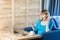 Side view portrait of beautiful emotional positive girl with blonde hair in blue blouse are sitting in cafe and working on laptop