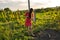 Side view portrait of beautiful teen girl with brunette lng hair wering red dress working in vineyard with rakes