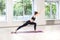 Side view portrait of beautiful young woman wearing in black pants and top working out against window, doing yoga or pilates