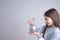 Side view portrait of the brunette girl in grey santa sweater that holds gray ney year`s toy in hands and looking at it