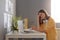 Side view portrait of Caucasian woman freelancer sitting at table in front of portable computer, feels fatigue, being tired and