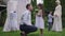 Side view portrait of Caucasian young man giving wedding bouquet to charming Middle Eastern flower girl as blurred bride