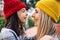 Side view portrait of cheerful little girl in red hat hugging her mom in yellow hat outside. Cute kid embracing her mother