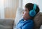 Side view portrait Child boy wearing headphones and looking out deep in thought, School boy in blue T-shirt listening to music,