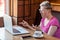 Side view portrait of emotional shocked young businesswoman in pink t-shirt is sitting in cafe, reading news and remotely working