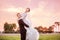 Side view portrait of happy bridegroom carrying bride on field during sunset