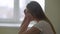 Side view portrait of sad depressed young woman sitting indoors thinking. Frustrated hopeless Caucasian slim beautiful