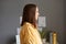 Side view portrait of serious assertive young adult woman with brown hair wearing yellow shirt posing in office, looking ahead