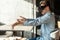 Side view portrait of suprised bearded young adult man in blue denim shirt sitting in cafe, wearing vr and watching video on