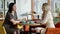 Side view portrait of two confident young women gossiping sitting at table in restaurant. Slim beautiful Caucasian