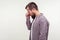 Side view portrait of unhappy bearded man in casual plaid shirt standing with head down, rubbing eyes and crying. white background