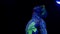 Side view portrait of a young caucasian man in blacklight bodyart. Performer standing with his head up then exhaling