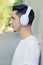 Side view portrait of young handsome guy leaning on wall and enjoying his favourite music using big white wireless headphones.