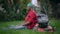 Side view portrait of young handsome thoughtful African American man sitting on grass leaning at lawnmower. Landscaper