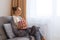 Side view portrait of young woman sitting on couch with popcorn, watching movie and eating popcorn, enjoying free time, looking at