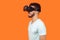 Side view of positive gamer, brunette man watching video or playing virtual reality game. isolated on orange background