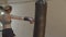 Side view of powerful woman punching and kicking heavy bag