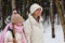 Side view of pre-teen girl in pink winterwear and her mother taking walk