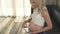 A side view of a pregnant blonde, who is checking fetal heartbeat. She looks at the belly and smiles.