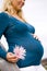 Side view of pregnant woman holding pink flower