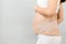Side view of pregnant woman in underwear wearing pregnancy bandage at gray background with copy space. Close up of orthopedic