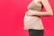 Side view of pregnant woman wearing elastic maternity band at pink background with copy space. Close up of orthopedic abdominal