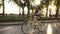 Side view pretty longhaired girl riding a bike on the street or boulevard in summer city park. Wearing pink coloured