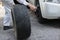 Side view of professional automotive mechanic man in uniform holding tire for fixing car at the garage background. Auto repair ser