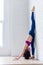 Side view of professional female athlete practicing yoga stretching her calves, hamstrings, thighs doing standing split