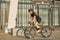 Side view of professional female cyclist in black cycling garment and protective gear riding bicycle in city, rushing