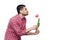 Side view profile portrait of handsome bearded young man in red checkered shirt standing and holding one tulip flower and smiling