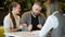 Side view of realtor and young couple sitting at office desk discussing property for sale. Happy couple became a house