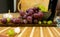 Side view of a red and yellow muscat colored grape, bottle of wine, garlic and a glass on a wooden board - still life