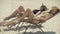 Side view of relaxed beautiful slim women sunbathing on sun loungers on sandy beach. Portrait of two gorgeous Caucasian