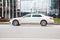 Side view rolling shot with white car in motion. Mercedes Maybach S Class driving along the street in city with blurred background