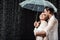 side view of romantic couple in white shirts standing under umbrella under raindrops