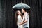 side view of romantic couple in white shirts standing under umbrella under raindrops